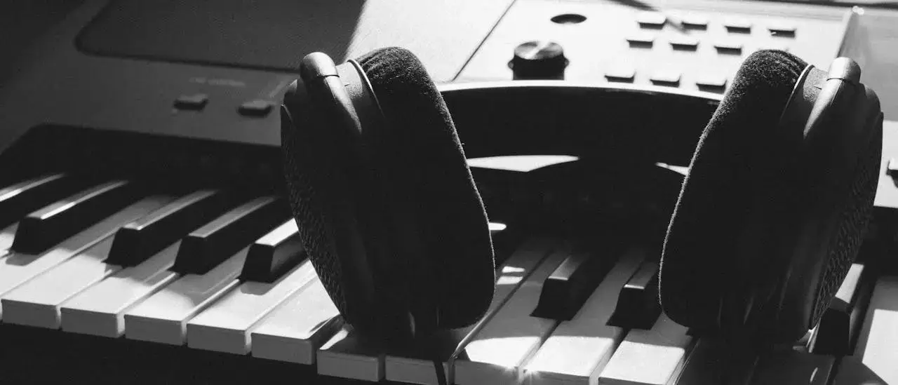 services-01 Close-up of headphones resting on piano keys, capturing the essence of music creation.
